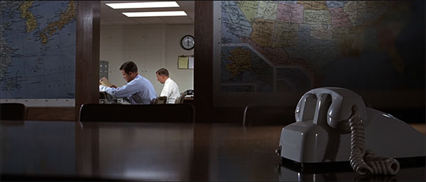 Composición con teléfono en primer término y científicos al fondo en The Andromeda Strain
