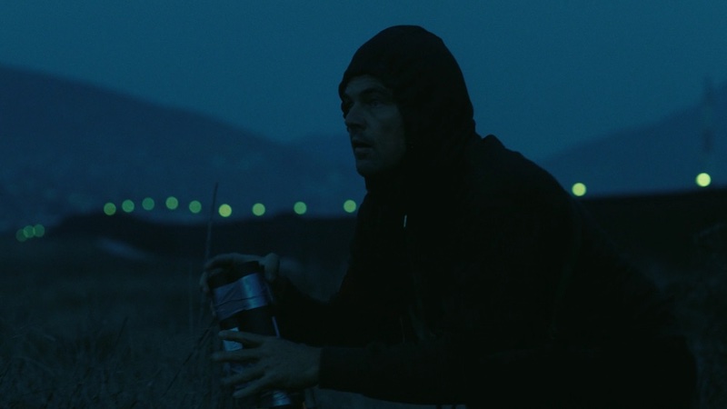 One Battle After Another, plano nocturno azulado con personaje encapuchado en exterior, fotografía de Michael Bauman