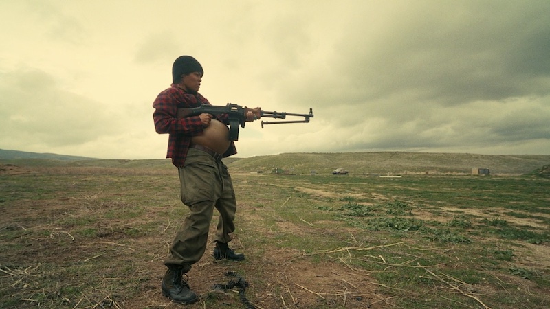 One Battle After Another, personaje armado en un descampado bajo cielo nublado, fotografía de Michael Bauman