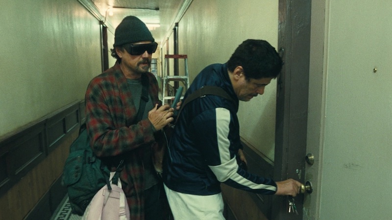 One Battle After Another, dos personajes entrando en un piso por un pasillo estrecho, fotografía de Michael Bauman