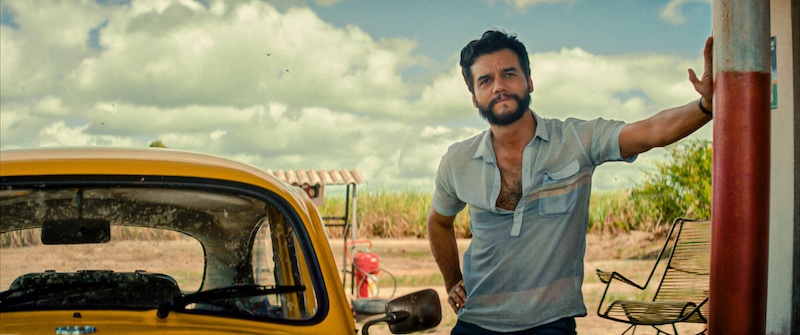 O Agente Secreto The Secret Agent 2025 Wagner Moura como Armando junto a un coche amarillo en exterior cálido de Recife