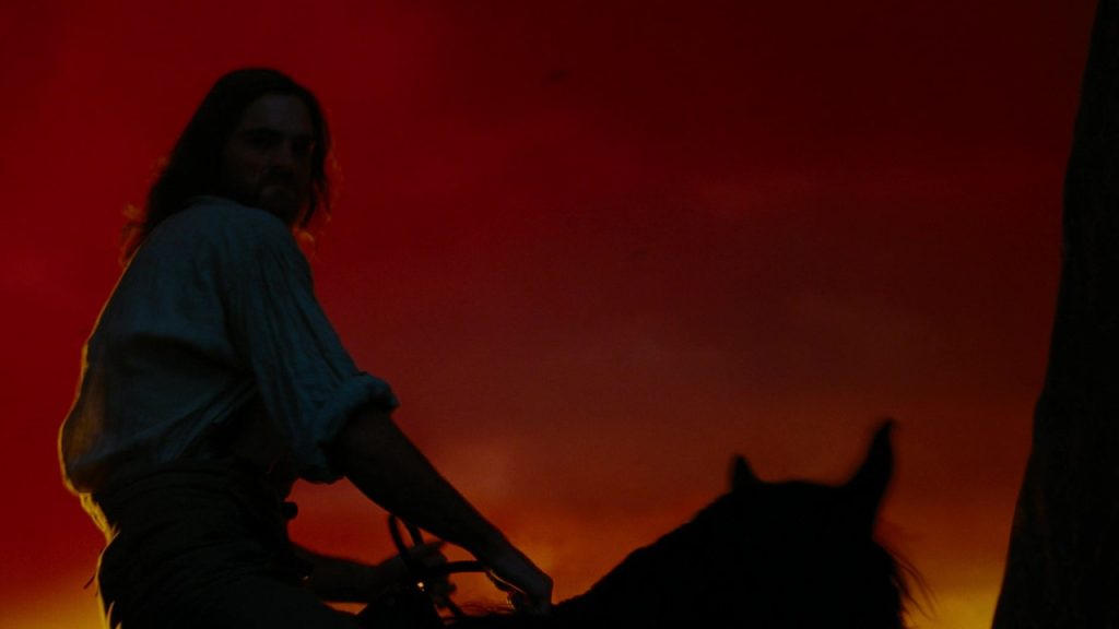 Heathcliff a caballo contra un fondo rojo estilizado en Wuthering Heights 2026, fotografía teatral de Linus Sandgren