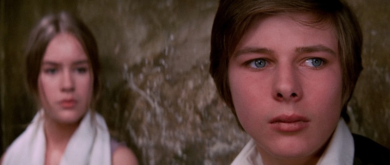 Primer plano anamórfico de John Moulder-Brown en La Residencia, con fondo desenfocado y tratamiento suave del rostro