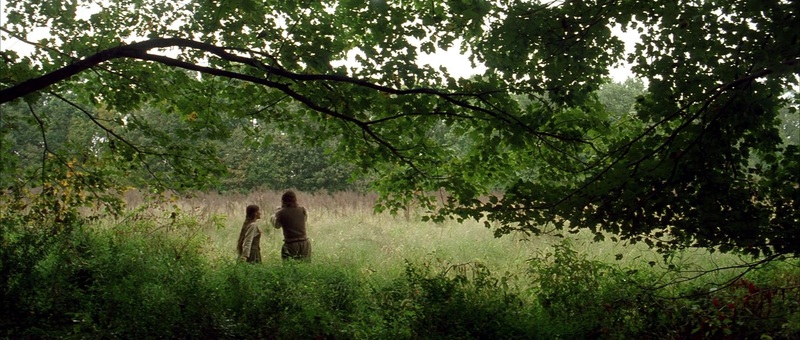 Plano general de dos figuras en un claro del bosque en The New World, fotografía de Emmanuel Lubezki